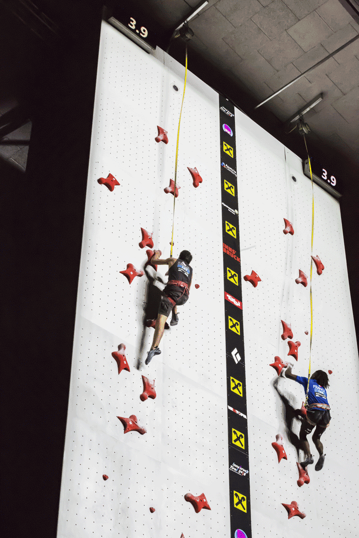 Speed climbers racing side by side up a speed climbing wall at the 2018 world climbing championship