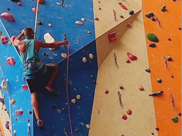 Young male climber interval climbing with Perfect Descent auto belay in a climbing gym